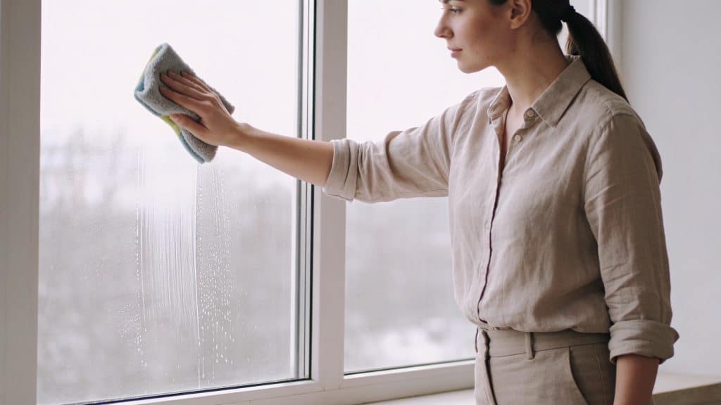 Femme essuyant une grande fenetre avec chiffon microfibre
