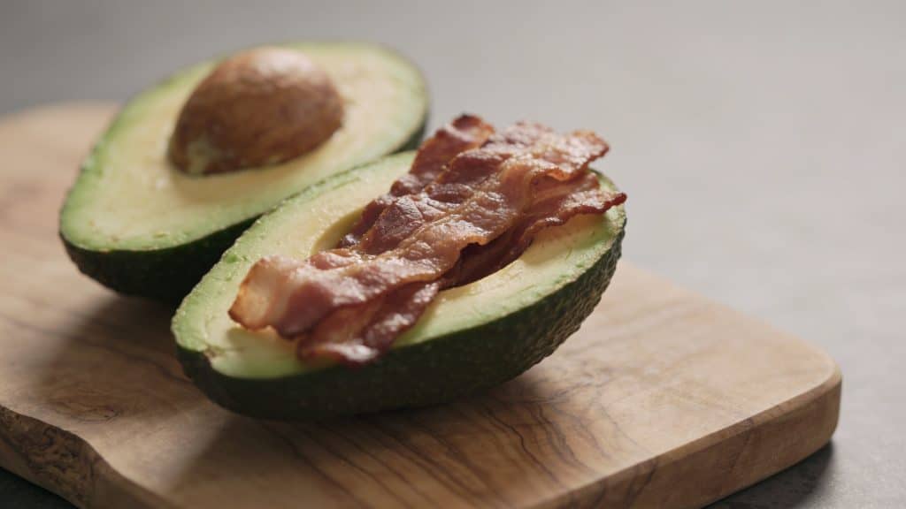 Gros avocat bacon coupe en deux sur planche