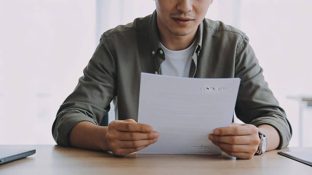 locataire assis devant bureau vide tenant contrat